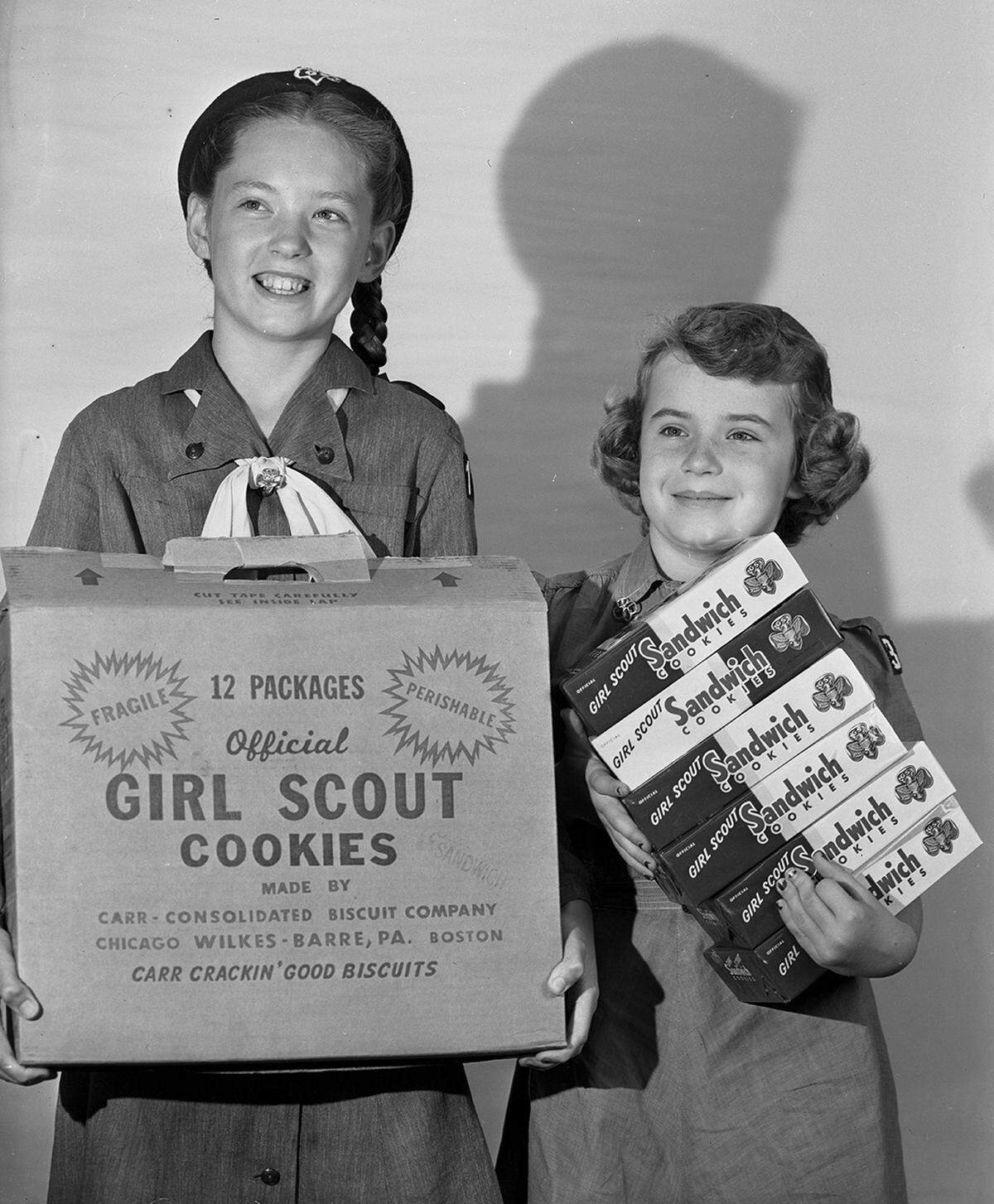 March 21, 1952: Girl Scout Joan Anderson and Brownie Scout Louise Ravenscroft were all smiling when front doors opened to their knock. They were finding Girl Scout cookies easy to sell on the first day of the cookie campaign. Joan is the daughter of Mr. and Mrs. James Anderson of 1915 Forest Park, and Louise is the daughter of Mr. and Mrs. W. G. Ravenscroft of 3202 Sixth Avenue.