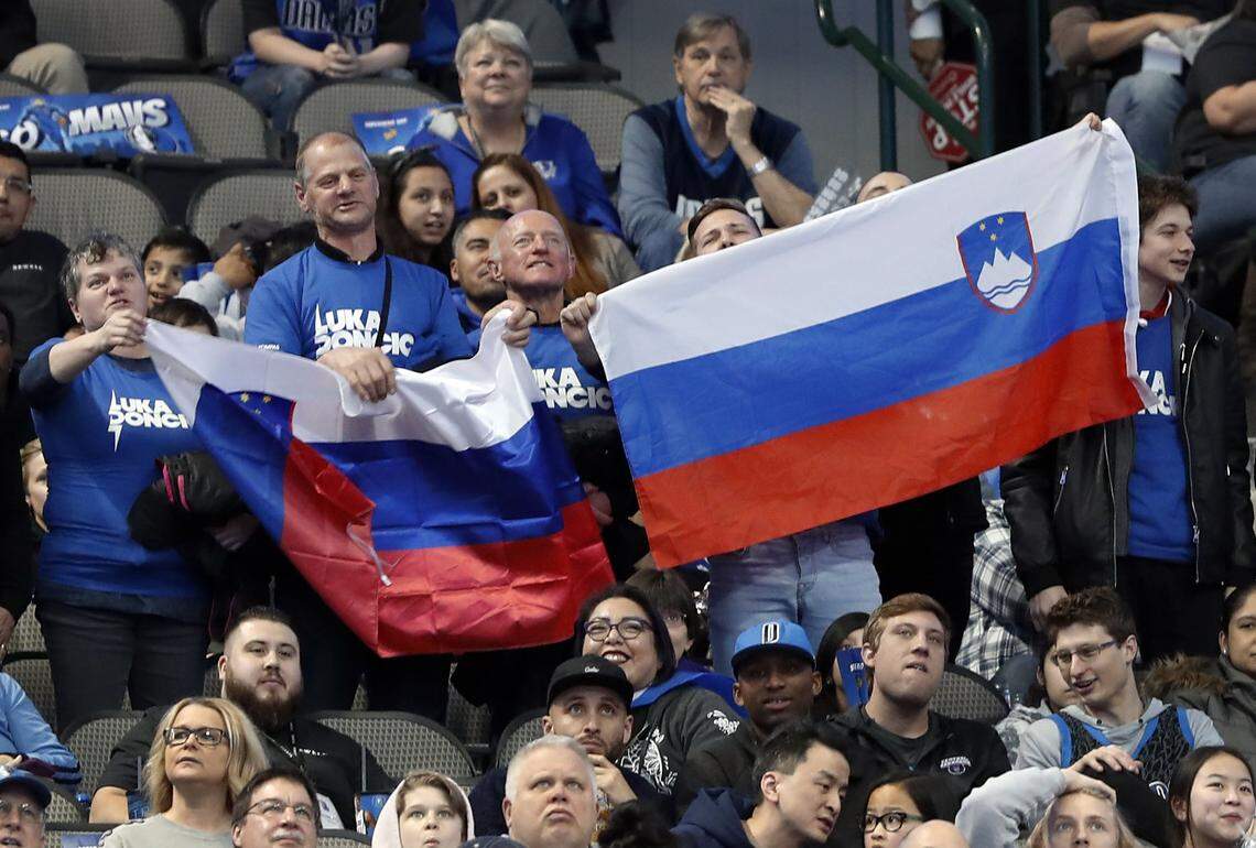 Fans hold up Slovenian flags as they cheer after Dallas Mavericks’ Luka Doncic scored a basket in the first half of an NBA basketball game against the Portland Trail Blazers in Dallas, Sunday, Feb. 10, 2019. (AP Photo/Tony Gutierrez)