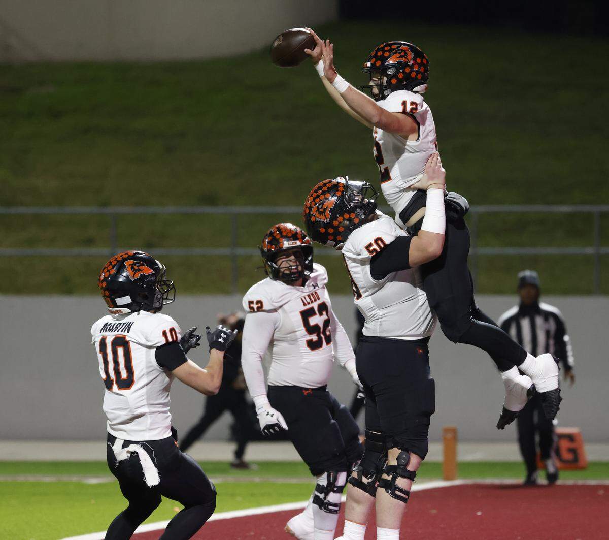 Aledo offensive lineman Grant Forman (50) lifts quarterback Lincoln Tubbs (12) after Tubbs scored one of his four first half touchdowns against Denton Ryan during the first half of a UIL Class 5A Division I Quarterfinal on Friday Dec. 05, 2025 at Northwest ISD Stadium in Fort Worth, Texas.