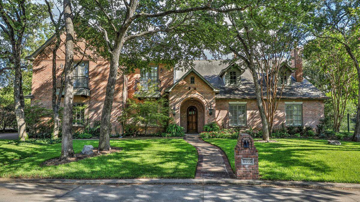 The home at 6105 Laurel Valley Court features a front yard with towering trees and manicured landscaping.