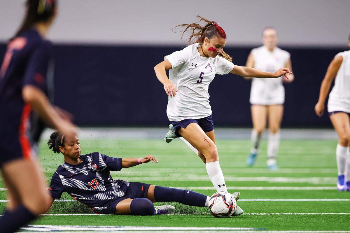 Grapevine midfielder Tatum Harig (5) leaps over a diving Frisco Wakeland defender with the ball in a Class 5A Division II UIL girls soccer state semifinal at the Ford Center on April 3, 2026 in Frisco, Texas.