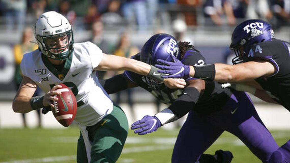 Baylor quarterback Charlie Brewer (12) tries to avoid the rush of TCU defensive ends Ochaun Mathis (32) and Colt Ellison (44) during the first half of an NCAA college football game, Saturday, Nov. 9, 2019, in Fort Worth, Texas. (AP Photo/Ron Jenkins)
