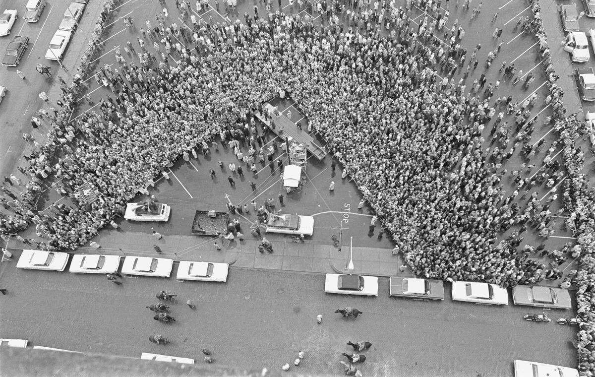 Aerial of crowd waiting to hear John F. Kennedy speak outside Hotel Texas, now the Hilton. A flatbed truck moved in place as a temporary stage. Mounted sheriff’s patrol did crowd control. Fort Worth, 11/22/1963