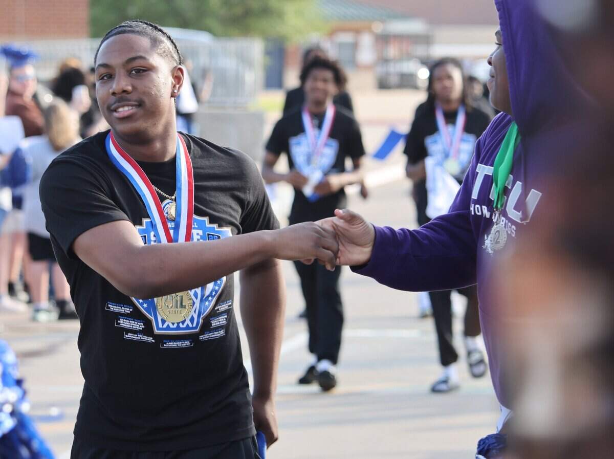North Crowley guard Kameron Price slaps hands with a football player during the Walk of Champions to celebrate the boys basketball team’s Class 6A Division I state championship Thursday, April 2, 2026, at North Crowley High School in Fort Worth.