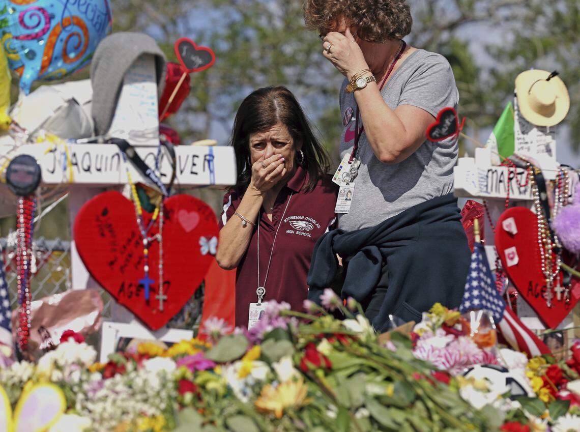 Margarita Lasalle, left, a bookkeeper and Joellen Berman, a guidance data specialist, look at a memorial Friday as teachers and school administrators returned to Stoneman Douglas High School for the first time since 17 victims were killed in a mass shooting at the school, in Parkland, Fla.