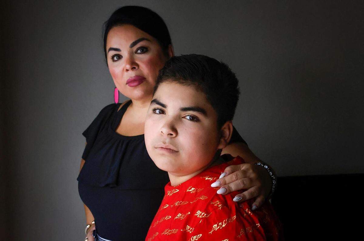 Elvia Espino stands beside her son, Alex, with her arm on his shoulder.