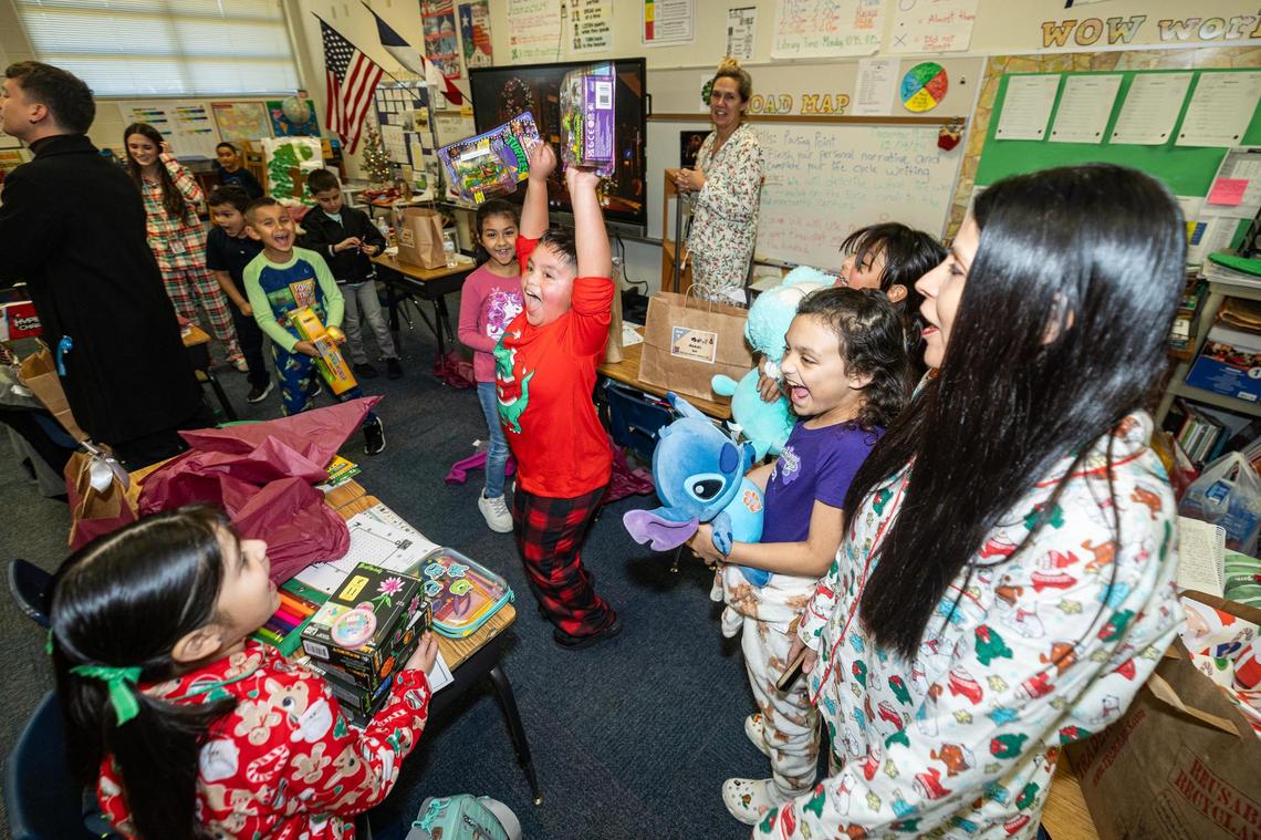 Second-grade students react to seeing their Christmas presents laid out for them on their desks in their classroom at Alice Contreras Elementary School in Fort Worth on Thursday, Dec. 19, 2024.