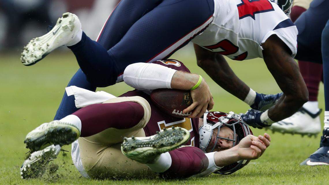 Washington Redskins quarterback Alex Smith, bottom, slides under Houston Texans cornerback Johnathan Joseph (24) during the first half of an NFL football game, Sunday, Nov. 18, 2018, in Landover, Md.