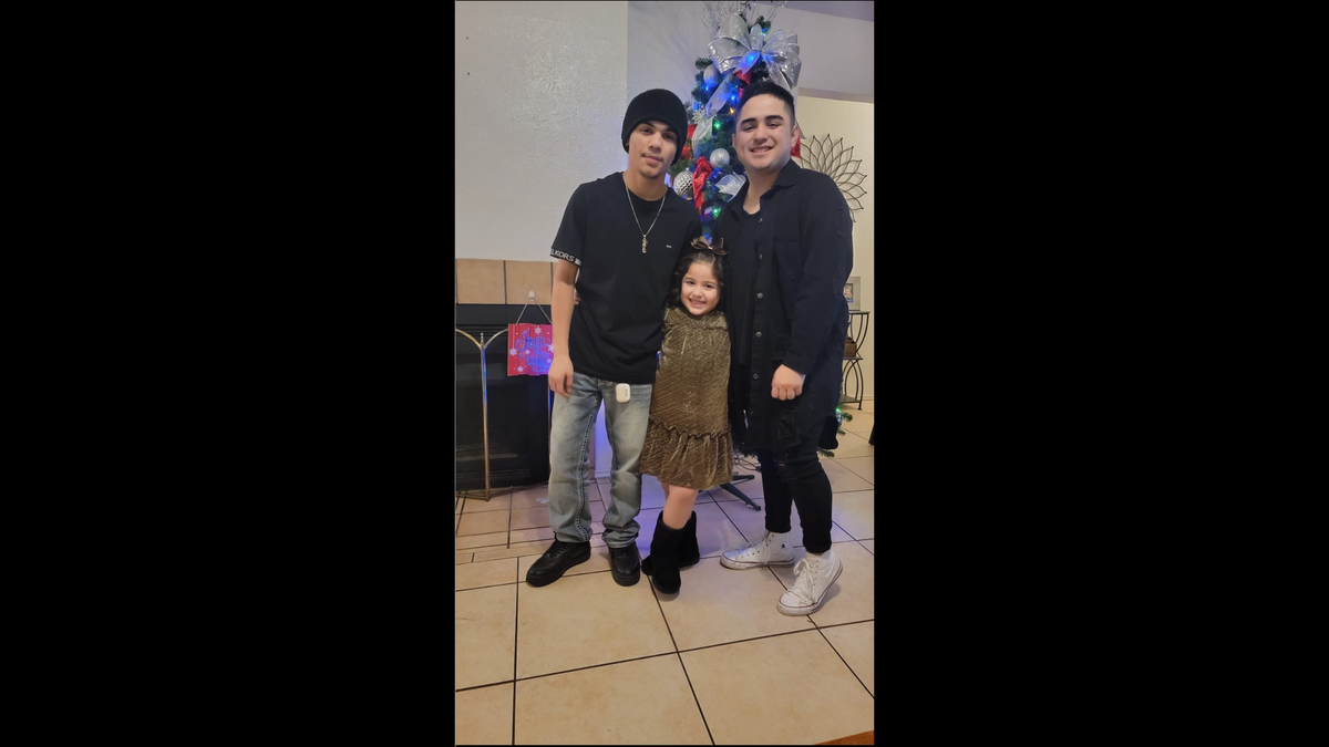 Emiliano (left), his little sister (middle) and Oliver (right) pose for a picture in front of a Christmas tree.