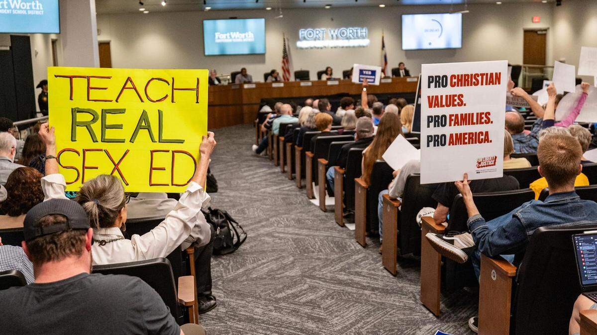 A supporter of the ‘HealthSmart’ curriculum and the ‘Choosing The Best’ hold opposing signs next to each other in the Fort Worth Independent School District school board meeting discussing the future of sex education at the Fort Worth ISD Administration Building in Fort Worth on Tuesday, Feb. 27, 2024.