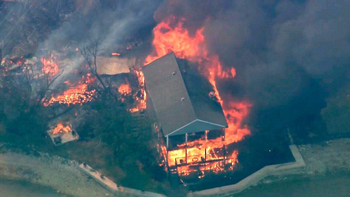 In this image taken from video, a structure burns during a wildfire in Palo Pinto County, Texas on Monday, July 18, 2022. A wildfire has burned several homes and resulted in about 300 homes being evacuated around Possum Kingdom Lake in North Texas amid sweltering temperatures and dry conditions, authorities said.