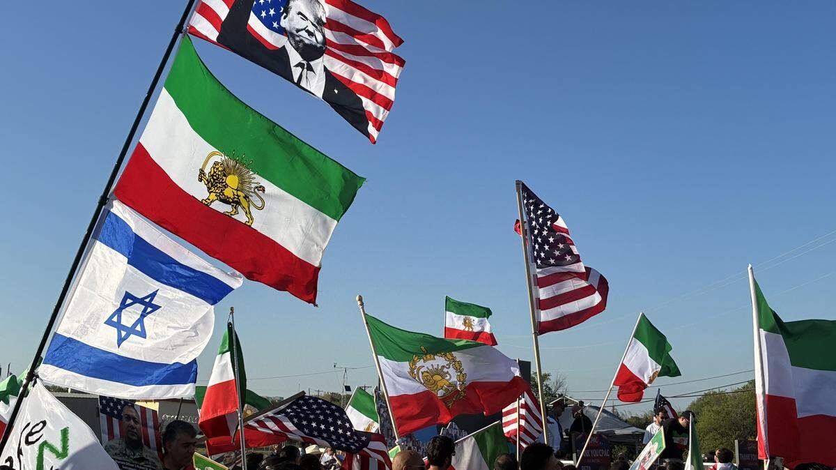 Demonstrators hold flags at an Iranian War Rally on March 26 near the Gaylord Texans Resort and Convention Center where CPAC is being held.