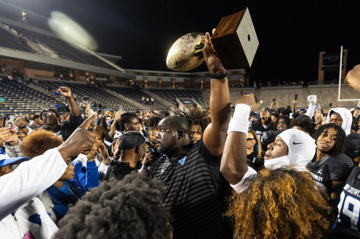 North Crowley head coach Ray Gates raises the trophy with his team after defeating Duncanville 36-34 in the Class 6A Division I state semifinal game at Eagle Stadium in Allen on Saturday, Dec. 14, 2024.