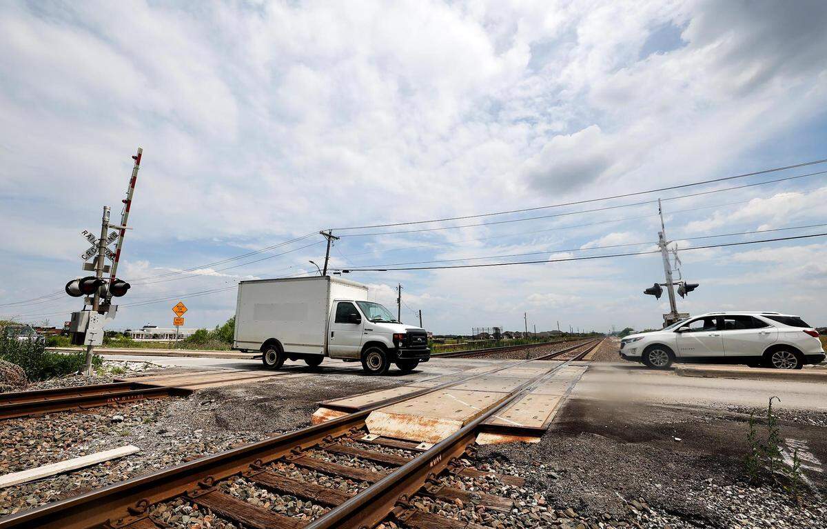 A truck and car are just about to cross a railroad crossing coming from opposite directions on a sunny day.