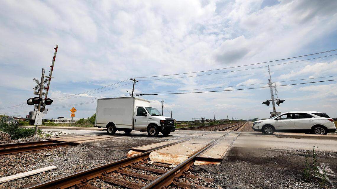 A truck and car are just about to cross a railroad crossing coming from opposite directions on a sunny day.