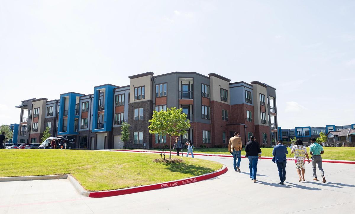 Guests walk toward the main lobby of The Opal, a mixed-income apartment community, for a ribbon cutting and reception celebrating the affordable housing property’s grand opening on Thursday, April 17, 2025.