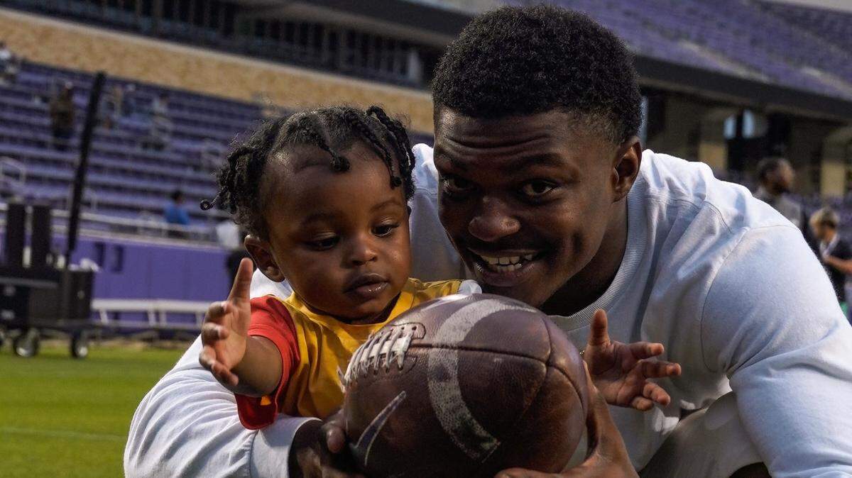 TCU safety Bud Clark and his son Kenzo share a moment during a TCU spring football practice on Friday at Amon G. Carter Stadium.