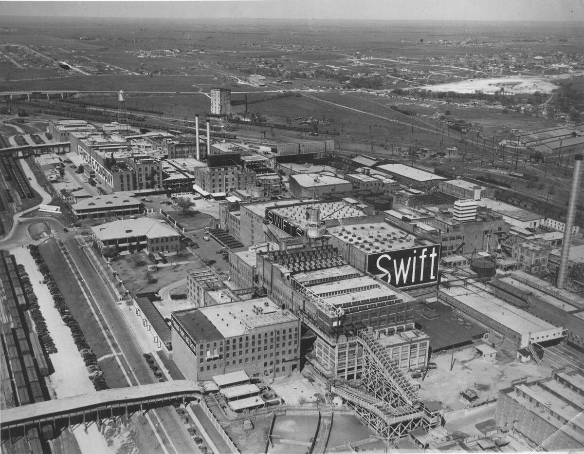 A 1930s aerial view of the Swift and Armour meat packing plants on the east end of the Fort Worth Stockyards, looking north-northeast. Packers Street is visible on the left foreground; the Armour building is identified by its name painted on the wall.