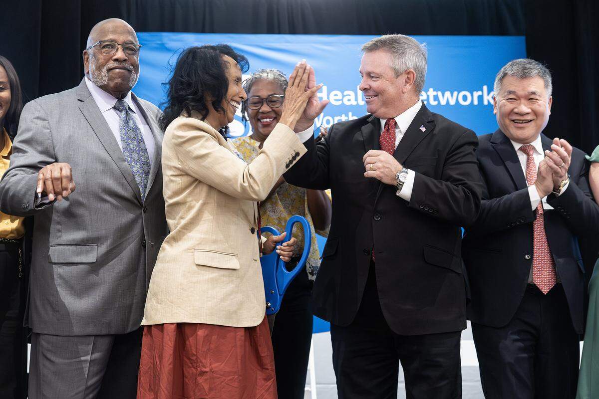 Karen Duncan, the President and CEO of JPS Health Network, high-fives Tarrant County Judge Tim OHare while surrounded by other dignitaries and officials after cutting the ribbon for the Psychiatric Emergency Center Open House at the facility in Fort Worth on Wednesday, Sept. 10, 2025. 