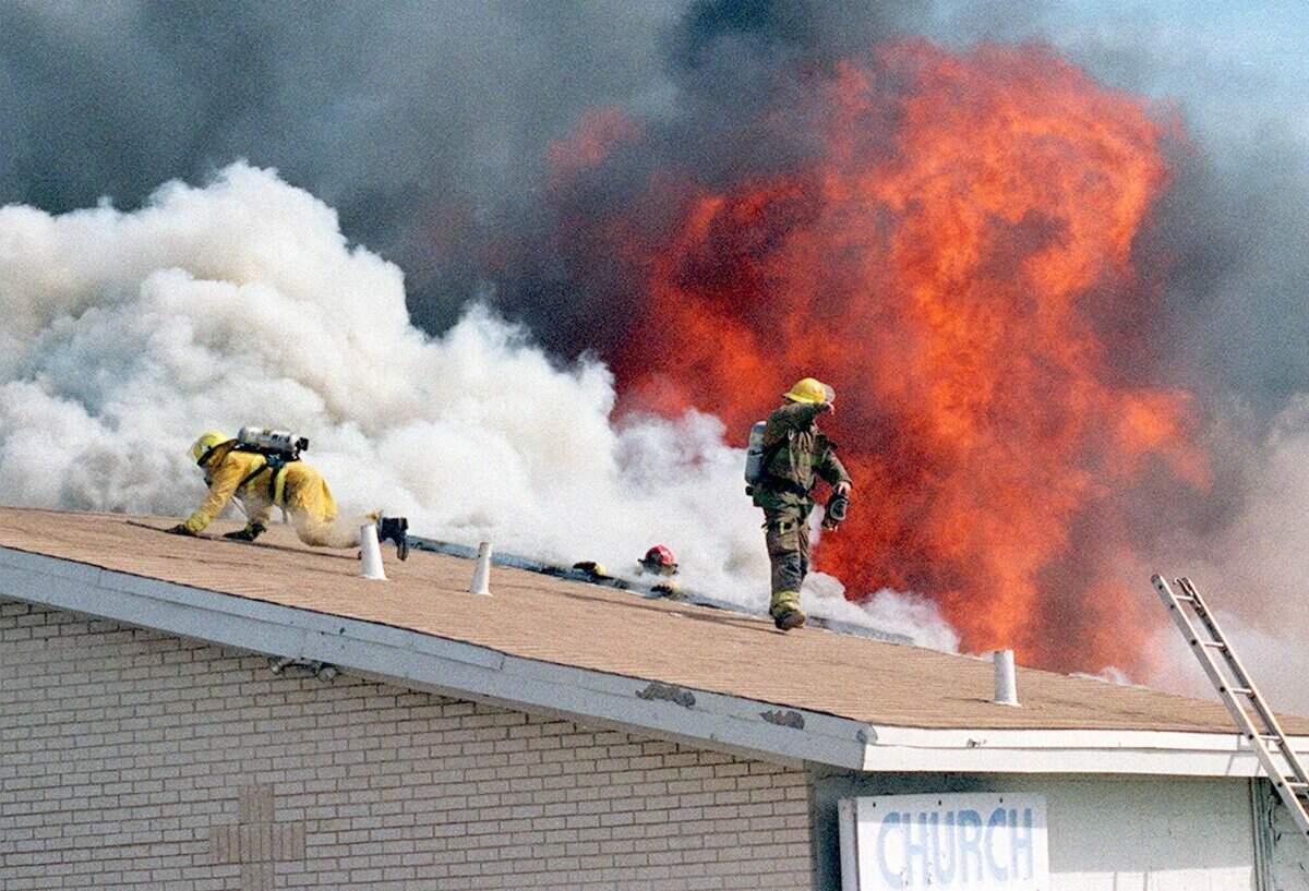 Volunteer firefighters are caught off guard as a roof collapses at the Precious Faith Temple in Lake Worth, Texas, Monday, Feb. 15, 1999. A firefighter can be seen holding on in the center wearing a red hat. A wind-whipped blaze quickly destroyed the church, killing three other firefighters who were trapped inside when the roof collapsed. The three firefighters shown on top of the roof were injured and taken to local hospitals. (AP Photo/Fort Worth Star-Telegram, Belinda Hart)