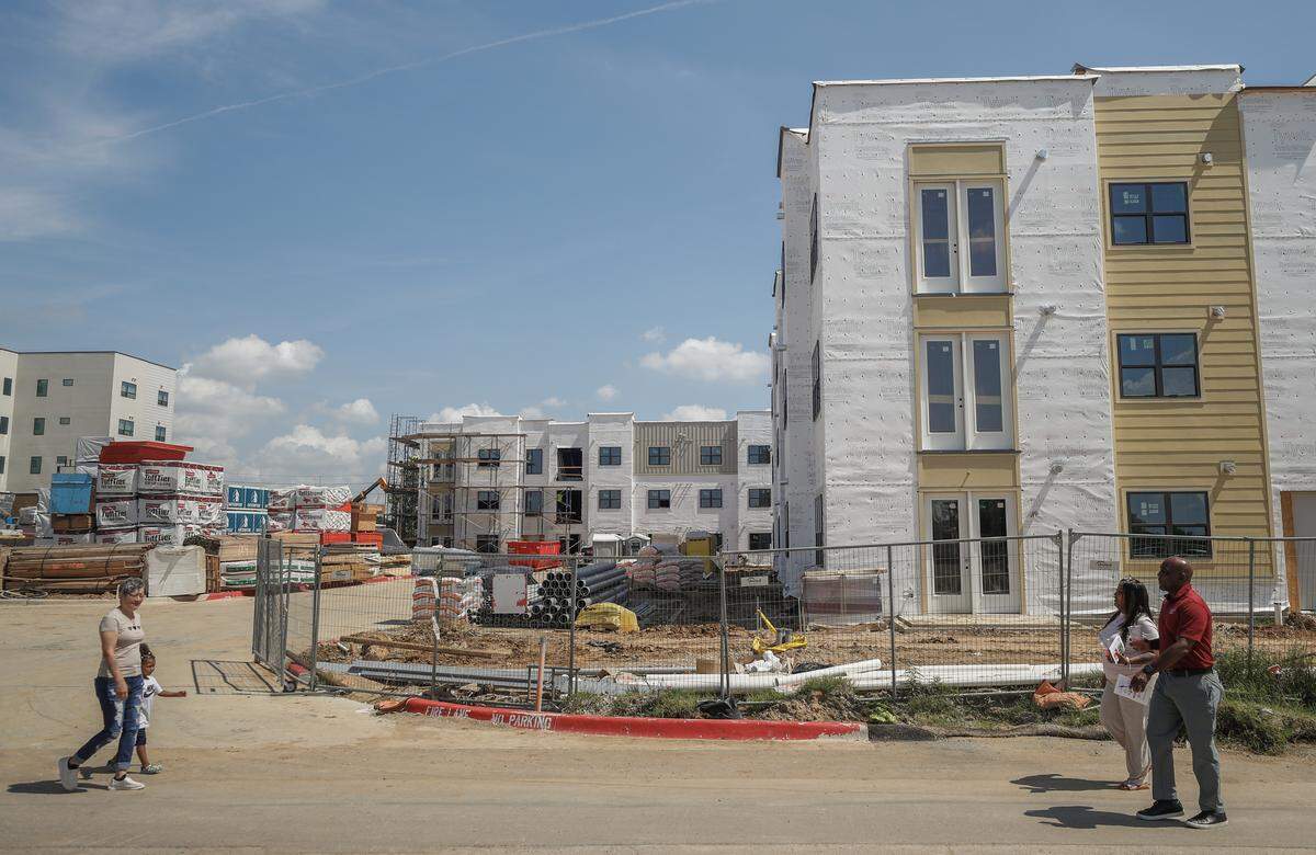 Residents and guests walk past the construction of Hughes House Apartments during a groundbreaking of Hughes House II in east Fort Worth on June 2, 2026. There will be a total of 542 mixed-income units in Hughes House once construction is completed.