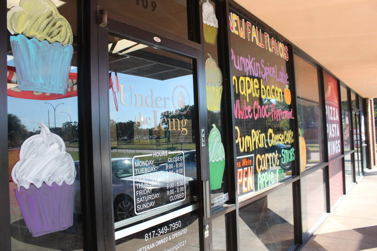 The storefront of Under the Icing, a bakery that lets customers customize their cupcakes, lists seasonal flavors on its window at 3601 SW Green Oaks Blvd. in Arlington.