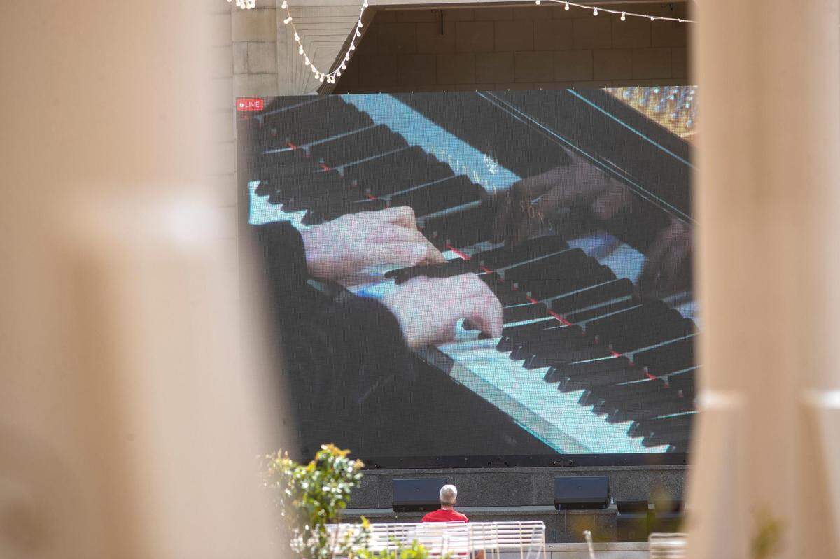 A spectator watches the 2022 Van Cliburn International Piano Competition finals on a livestream in Sundance Square on Saturday, June 18, 2022, in Fort Worth, Texas.