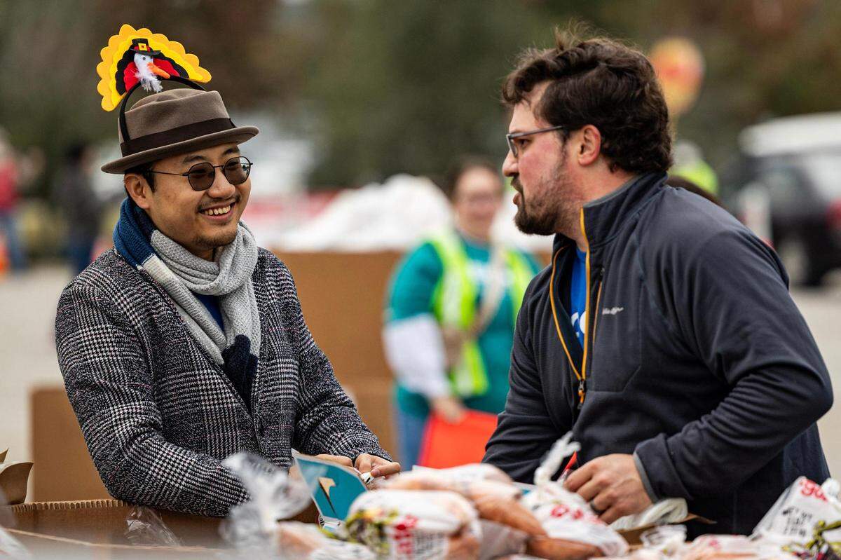 Bingchen Ji, left, and Dan Ingram share a laugh together while volunteering at the 4th annual Thanksgiving Mobile food distribution at AT&T Stadium in Arlington on Friday, November 17, 2023.