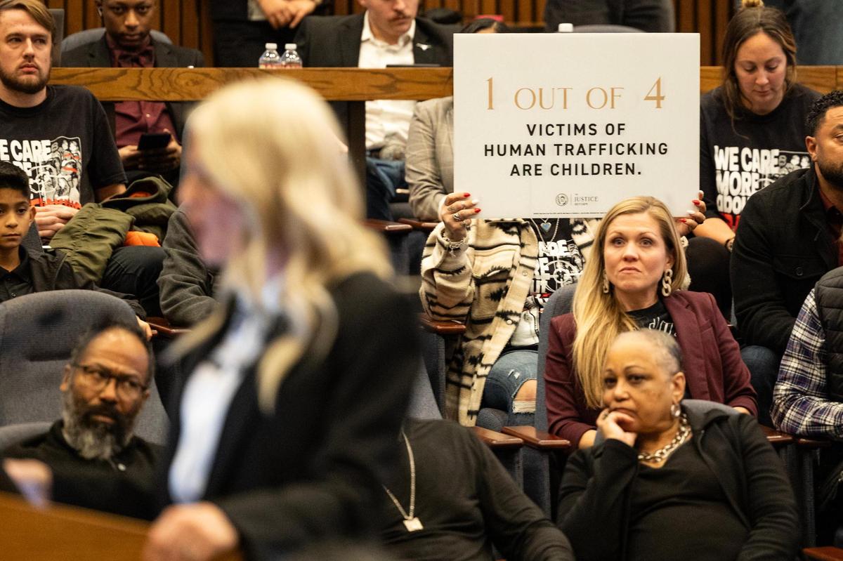 A Mercy Culture supporter holds up a sign behind Heather Schott, the co-lead pastor of Mercy Culture Church, as she speaks to the council members advocating for the approval of a proposed human trafficking victim shelter during a city council meeting in Fort Worth on Tuesday, Oct. 10, 2024.