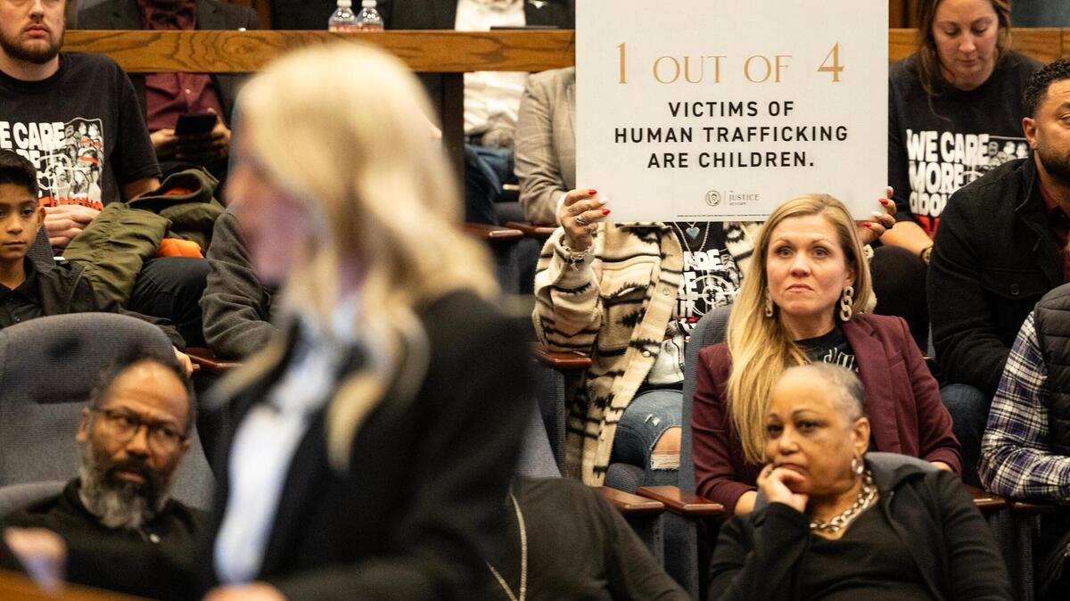 A Mercy Culture supporter holds up a sign behind Heather Schott, the co-lead pastor of Mercy Culture Church, as she speaks to the council members advocating for the approval of a proposed human trafficking victim shelter during a city council meeting in Fort Worth on Tuesday, Dec. 10, 2024.
