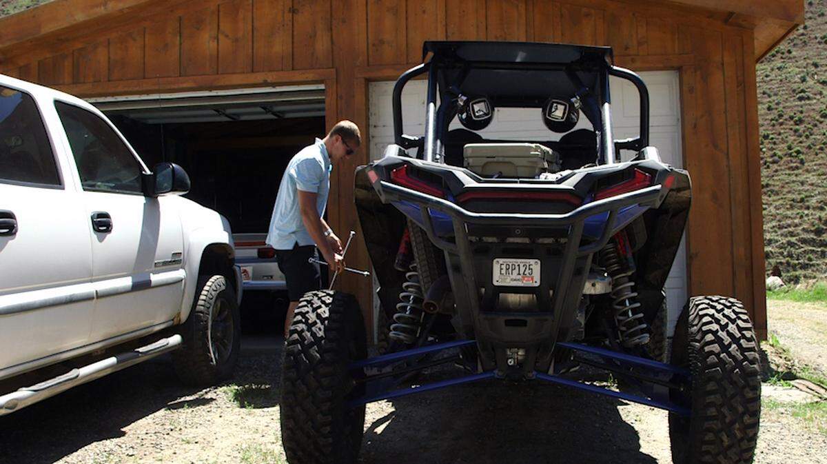 Leighton Vander Esch fixes the tire on his first big purchase as an NFL player: the two-seater Polaris RZR all-terrain vehicle.
