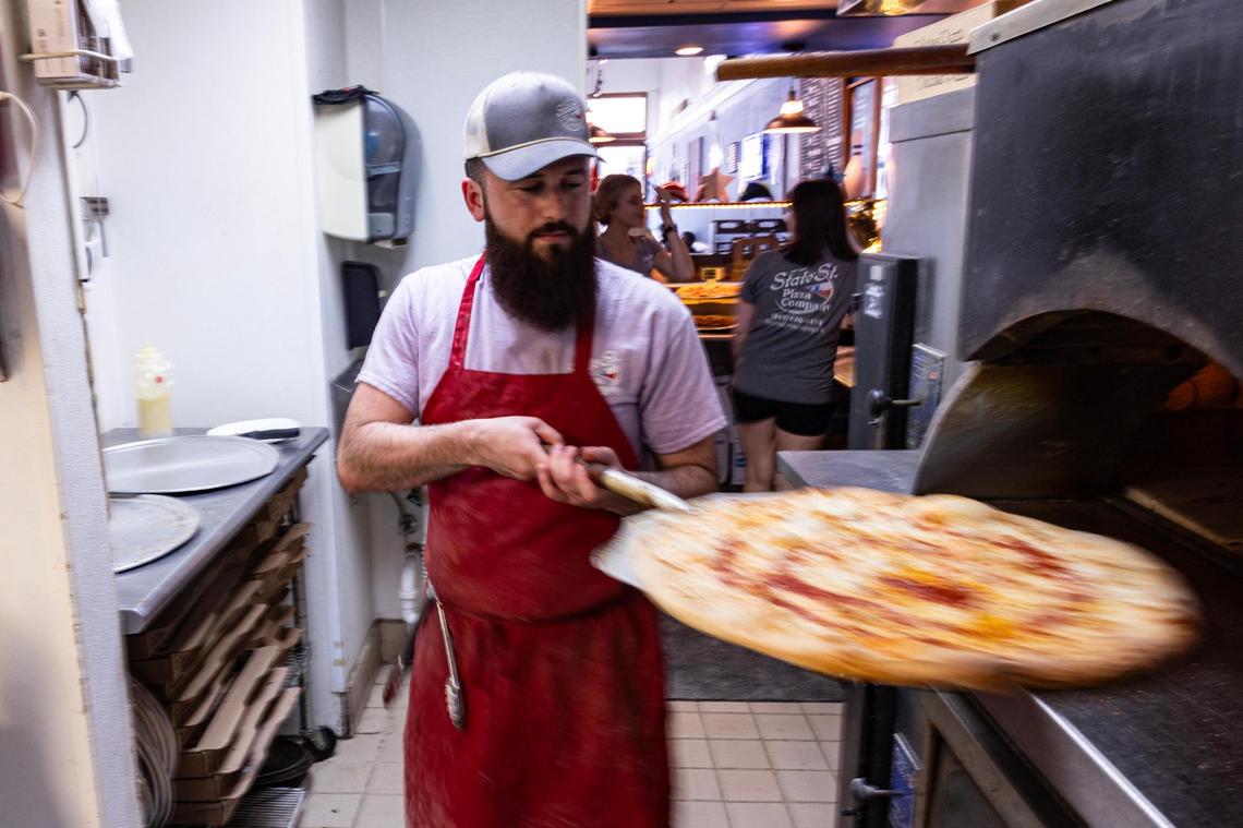 Kitchen manager Trey Pittman takes a finished pizza out of the oven during the lunch rush at State Street Pizza Company in Decatur on March 29, 2025. Pittman, who has been with State Street since it opened in 2020, believes the population growth and development in Decatur will result in business “booming.”