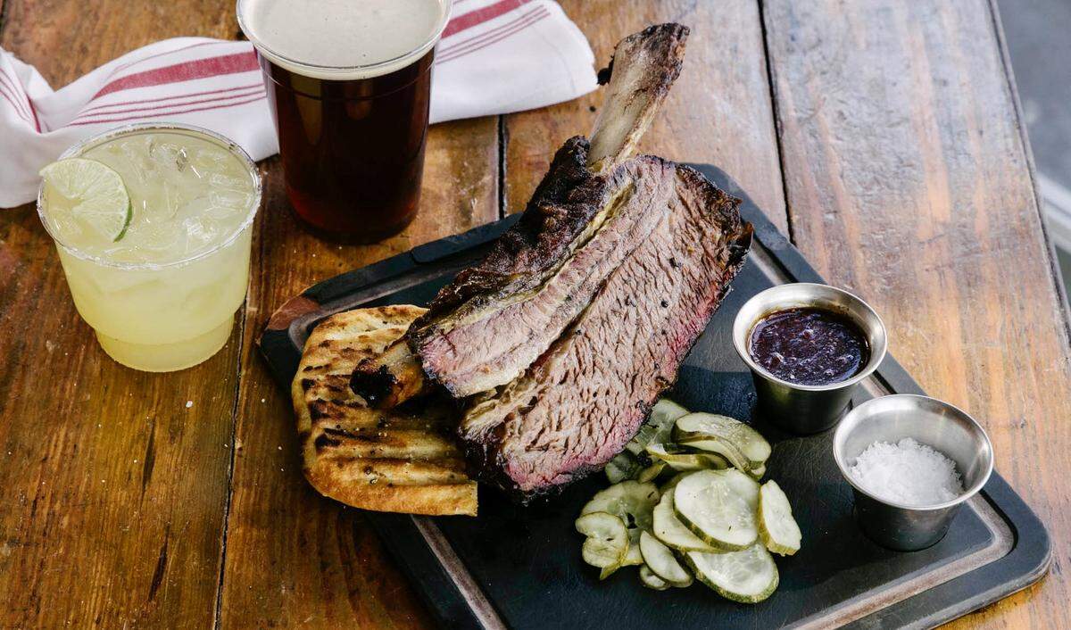 A beef rib with ancho glaze and house pickles at Woodshed Smokehouse.