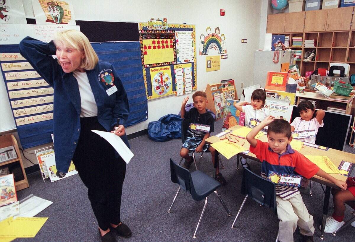 Aug. 14, 2000: Mary Jane Wood tells her kindergarten students to give themselves a pat on the back after a successful first day of school at Western Hills Primary School, a new campus.