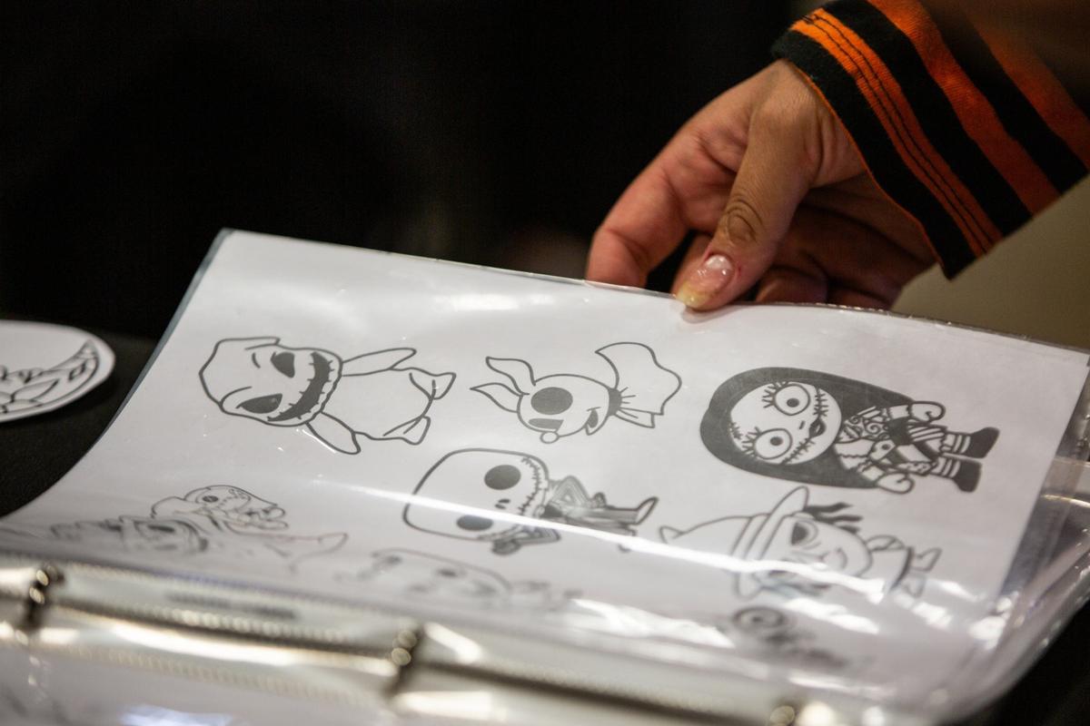 An attendee flips through pages with tattoo designs during Fort Worth Tattoo Arts Festival on Friday, June 7, 2024, at the Fort Worth Convention Center. Artists displayed various designs for attendees to choose from.