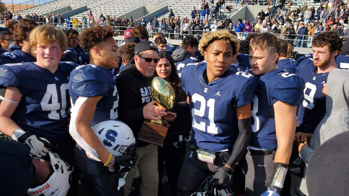 Fort Worth All Saints coach Aaron Beck holds the TAPPS state semifinal trophy with his players after the Saints defeated Fort Worth Christian 35-8 on Friday, November 25, 2022 at the Birdville Fine Arts/Athletic Complex in North Richland Hills