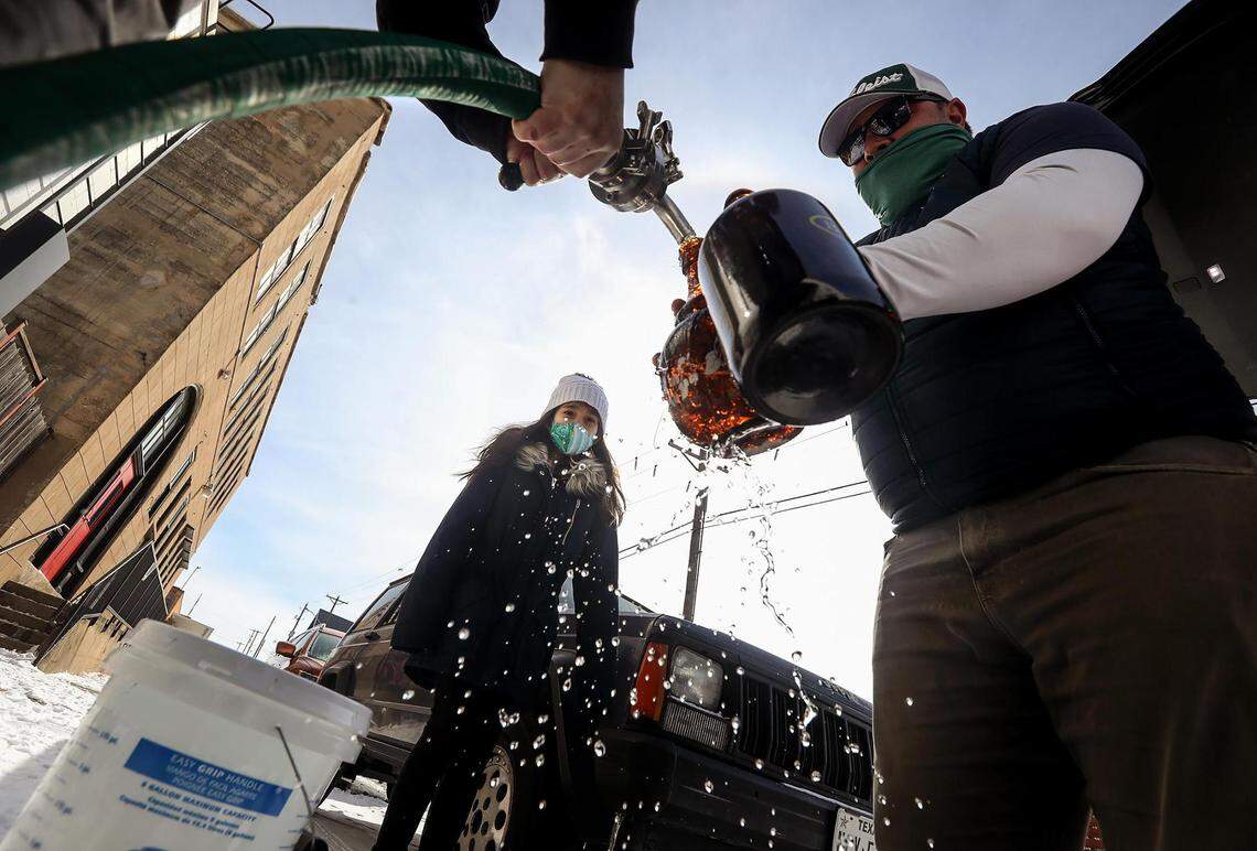 Macy Moore, co-owner of HopFusion Ale Works, left, fills up growlers with water for Aaron Villanueva, right, as Isabel Villanueva, 9, watches on Feb. 18, 2021. The brewery had 2,000 gallons of clean, drinkable water is it giving away to anyone in need.