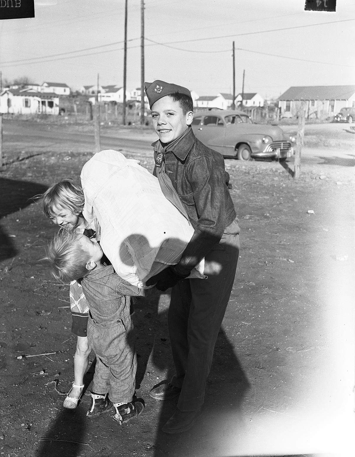 Dec. 23, 1952: The Goodfellows are filling the arms of children such as these. Here Kenneth Fallin, a Boy Scout helping with the Goodfellow deliveries, has to assist with this heavy sack. Its weight, however, meant it will be a Merry Christmas for these little children.