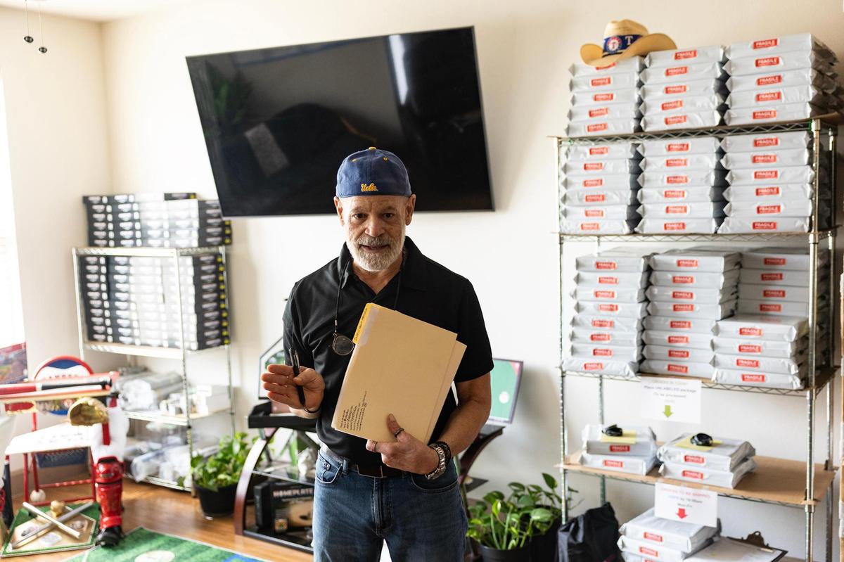 Miguel Otero, the creator of Homeplate USA, shows the inventory he has of the game in his apartment in Grapevine on Wednesday, April 16, 2025. Otero invented Homeplate USA, a baseball board game, when he was 11. Now retired at 67, he began producing and selling the game in March out of his apartment.