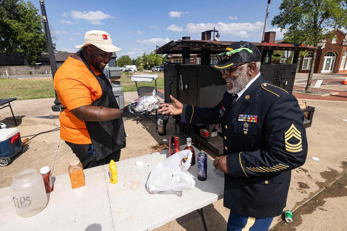 Allen Washington of Ali Turkey Legs DFW, left, serves former Master Sgt. Jerome Smith, right, an order of turkey legs during the Freedom Vibes Juneteenth Block Party in Fort Worth on Saturday, June 21, 2025.
