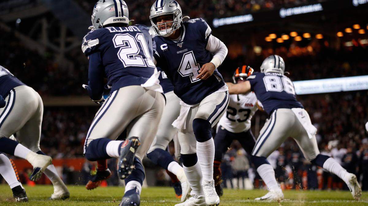 Dallas Cowboys quarterback Dak Prescott (4) hands the ball off to running back Ezekiel Elliott (21) against the Chicago Bears during an NFL football game, Thursday, Dec. 5, 2019, in Chicago. The Bears won 31-24.