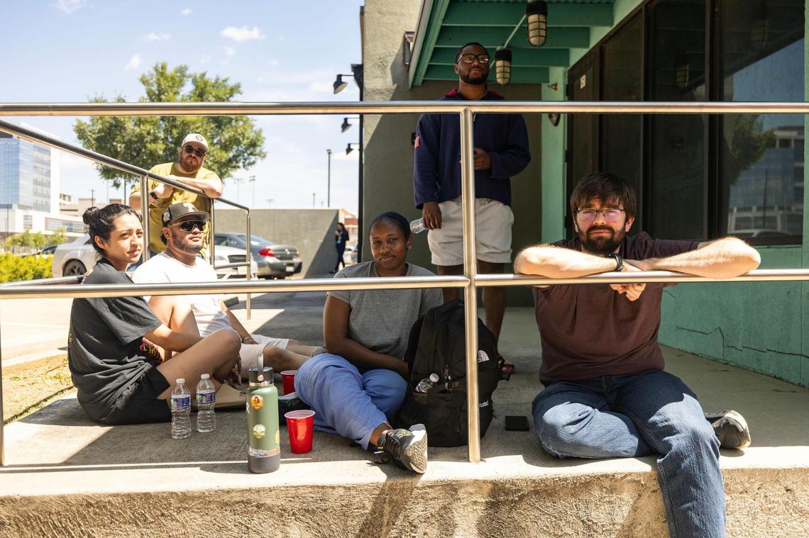 Displaced residents wait in the shade for clearance to access their apartment units on Tuesday, June 24, 2025, following a six-alarm fire at the Cooper Apartments in Near Southside Fort Worth the previous day.