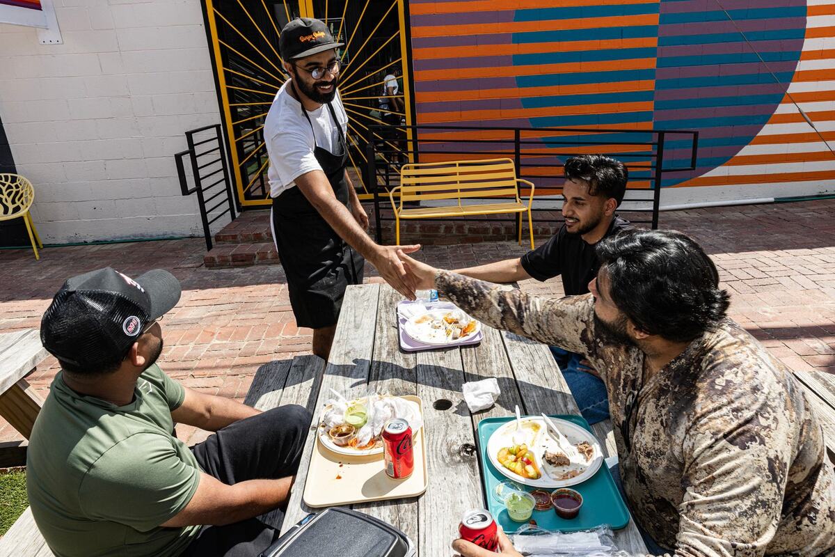 Zain Shafi, the owner of Sabar BBQ, speaks with Rafay and Ali Syed along with Zuni Waseem while they eat their food from Sabar BBQ in Fort Worth on Saturday, Aug. 31, 2024. Shafi said not only is he introducing Pakistani food to Texans, he also wants to introduce Texas barbecue to Muslims, who might also be hesitant to try it due to a possibility of cross contamination with pork.