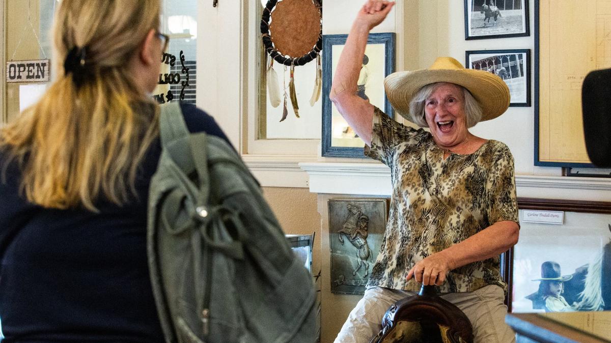 Elaine Booth poses for a photo pretending to ride a horse at the Stockyard Museum in Fort Worth on Wednesday, July 10, 2024. Booth is from South Africa and was visiting her daughter who lives in Austin.