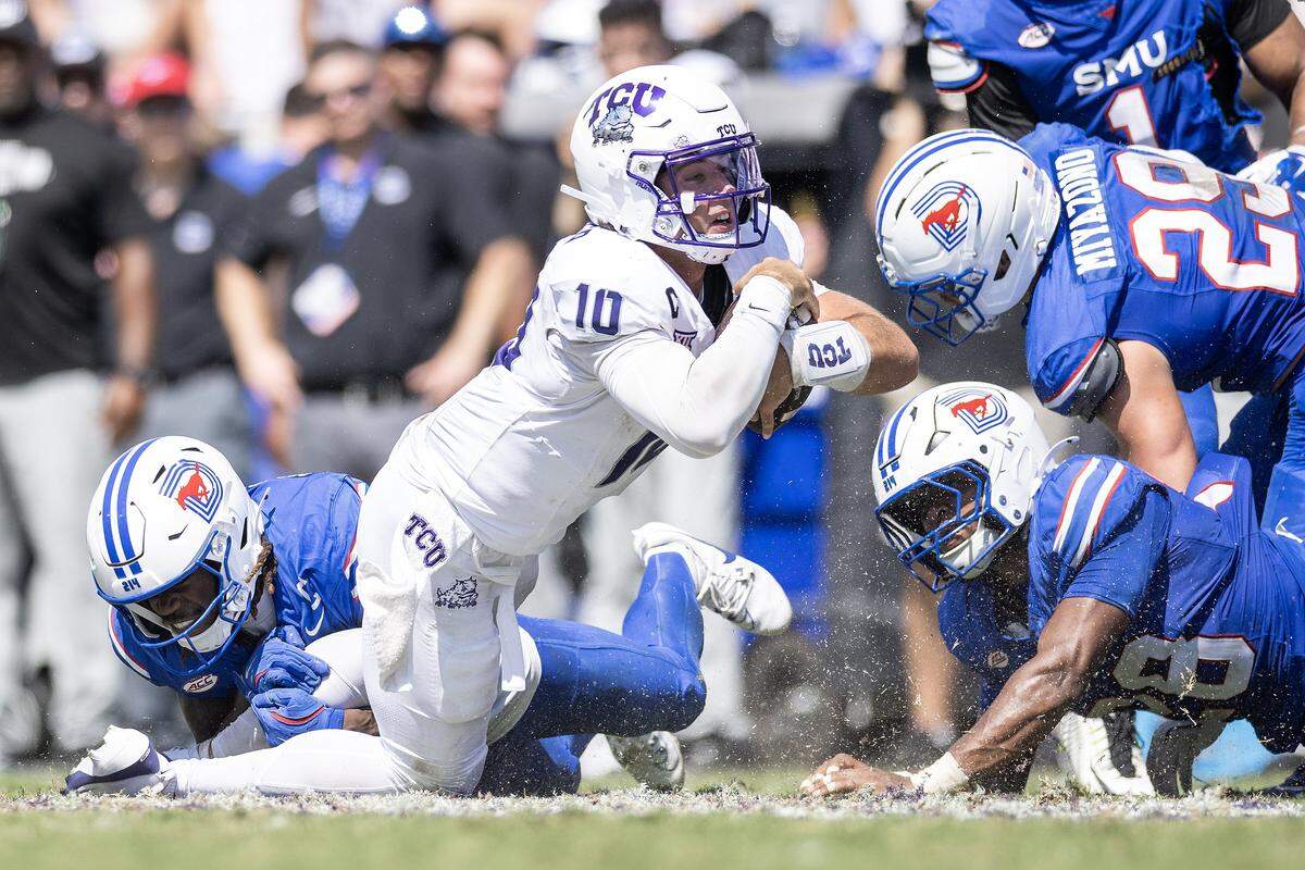 TCU quarterback Josh Hoover (10) gets tackled by multiple SMU defenders in the second half of an NCAA football game between TCU and SMU at Amon G. Carter Stadium in Fort Worth on Saturday, Sept. 20, 2025. TCU won 35-24 in the final Iron Skillet Rivalry game.