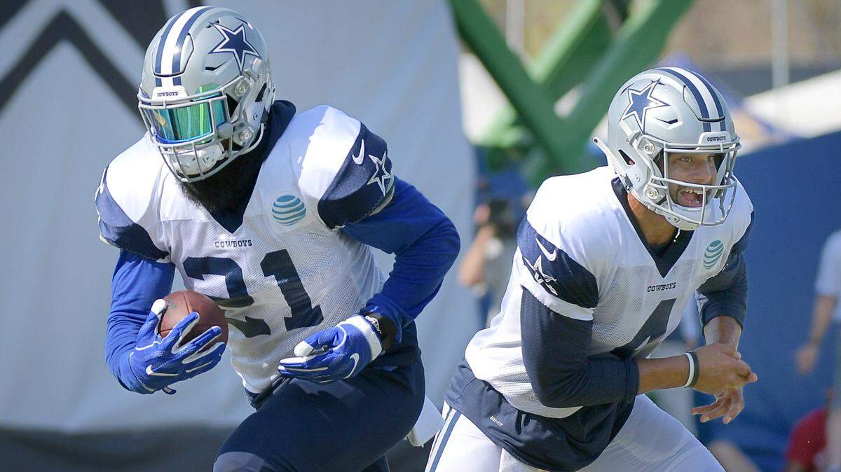Dallas Cowboys quarterback Dak Prescott (4) hands the ball off to running back Ezekiel Elliott (21) during an afternoon practice at training camp in Oxnard, Calif.