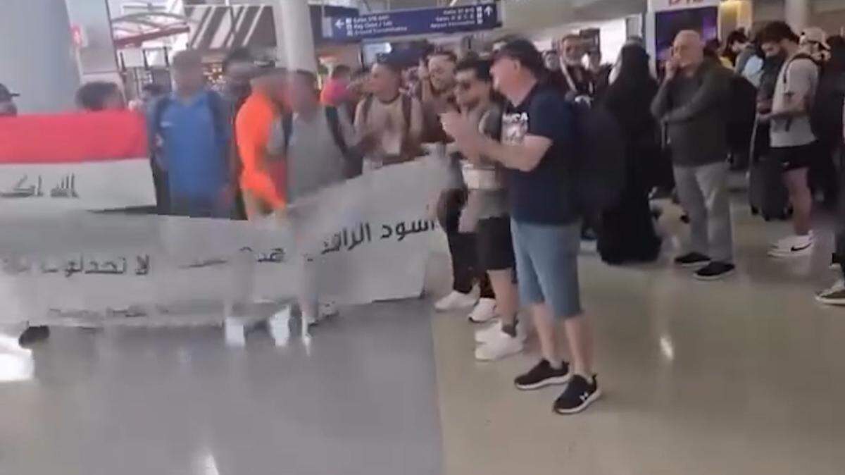 A man bursts through a banner held by Iraqi soccer fans at Dallas-Fort Worth International Airport on Monday, March 30, 2026.