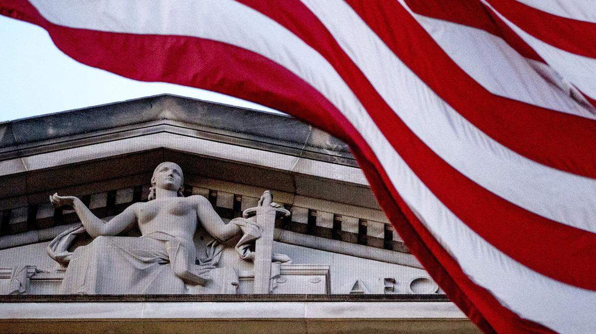 FILE - An American flag flies outside the Department of Justice in Washington, March 22, 2019. The Justice Department is giving $139 million to police departments across the U.S. as part of a grant program that would bring on more than 1,000 new officers. The grant funding being announced Thursday comes through the Justice Department’s Office of Community Oriented Policing Services and will be awarded to 183 law enforcement agencies. (AP Photo/Andrew Harnik, File)