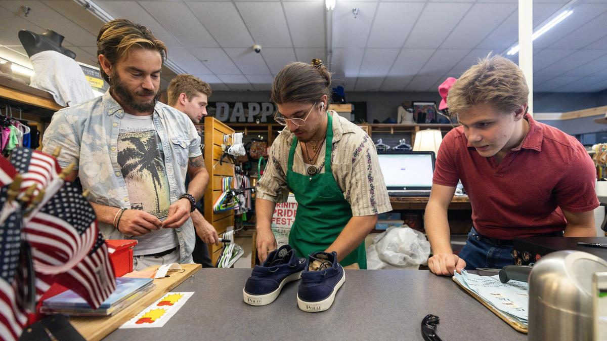 Nonprofit director Ryan Martinez, left, watches as volunteers Isiah Yanez, middle, and Kaiden Dais put price tags on shoes for sale at The Awareness Project store and cafe in Hurst in June. The Awareness Project, a local nonprofit organization aimed at reducing hunger, poverty and homelessness, is scheduled to close later this summer due to rising rent costs.