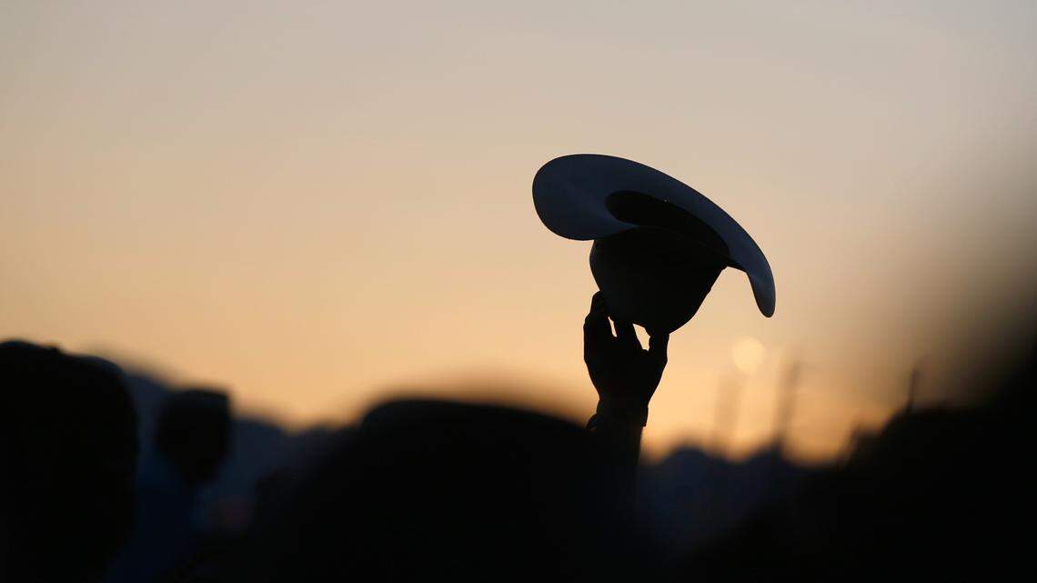 A cowboy hat held up with sunset light in the background.